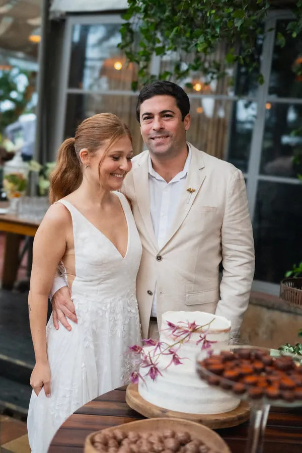 Os noivos ao lado do bolo, no dia do casamento