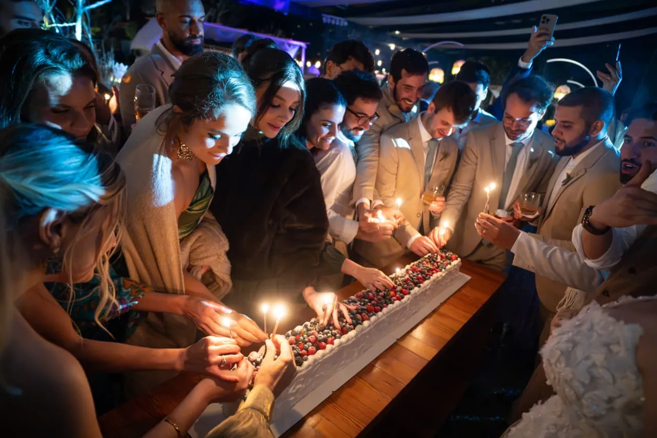 Convidados acendendo as velas do long cake da Brada, numa festa
