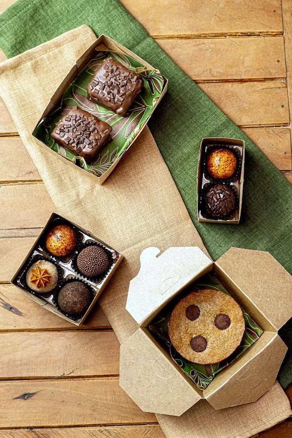 Brownies, caixinhas de brigadeiros e cookie embalados, vistos de cima