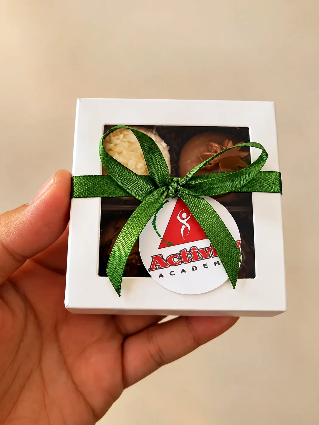 Caixinha de quatro brigadeiros com laço verde e a tag de um cliente