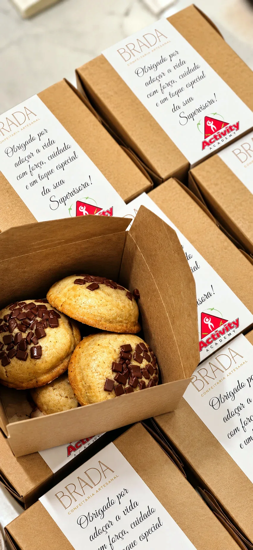 Cookies na caixa kraft com a cinta personalizada de um cliente